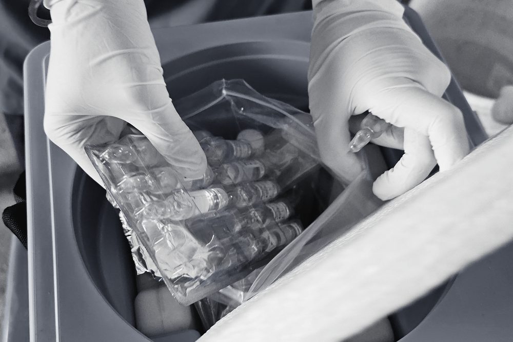 Gloved hands packing vials into an insulated cold box